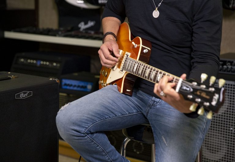 Person spielt E-Gitarre neben Verstärker