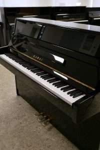 Schwarzes Klavier stehend, offene Tastatur.
