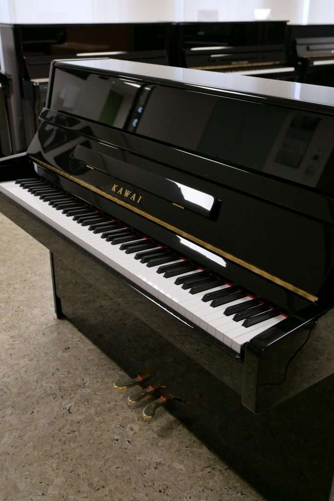 Schwarzes Klavier stehend, offene Tastatur.