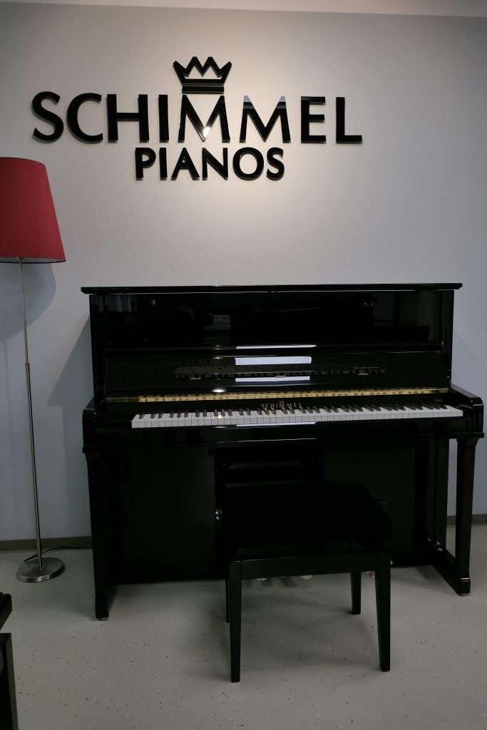 Schimmel-Piano vor Firmenlogo an der Wand