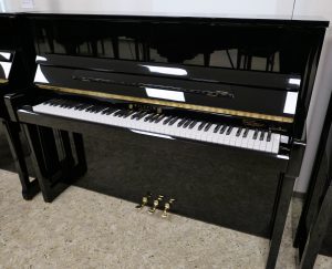 Schwarzes Klavier mit Klaviertasten und Pedalen.