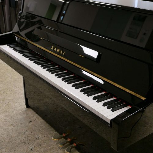Schwarzes Klavier stehend, offene Tastatur.
