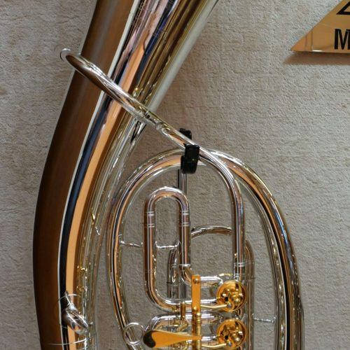 Silberne Tuba mit vier Ventilen an der Wand.